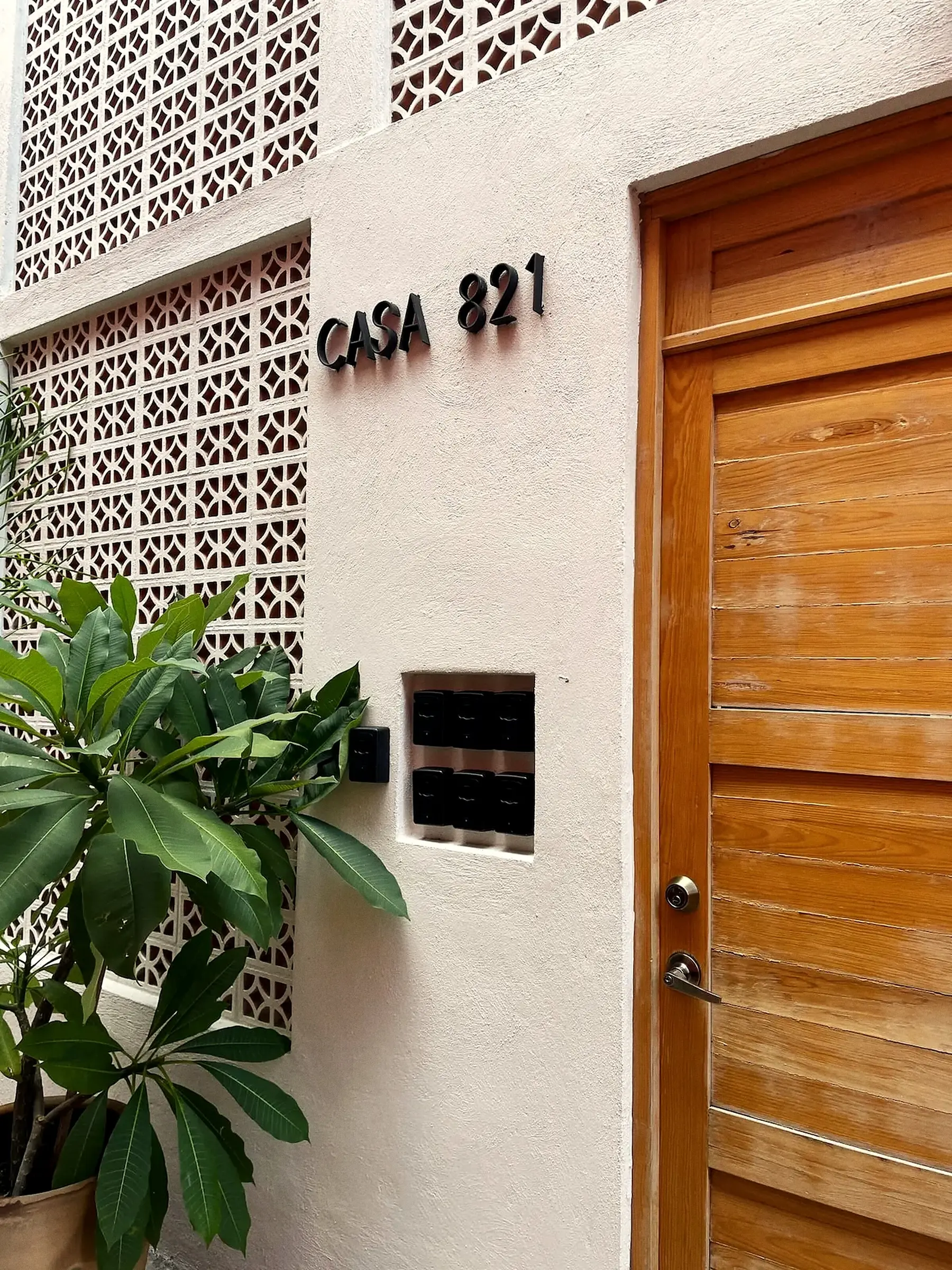 La entrada de Casa 821: la celosía, el letrero y la puerta de madera